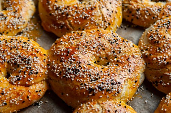 Egg-glazed twisted bread rings covered in white sesame and black nigella seeds on parchment