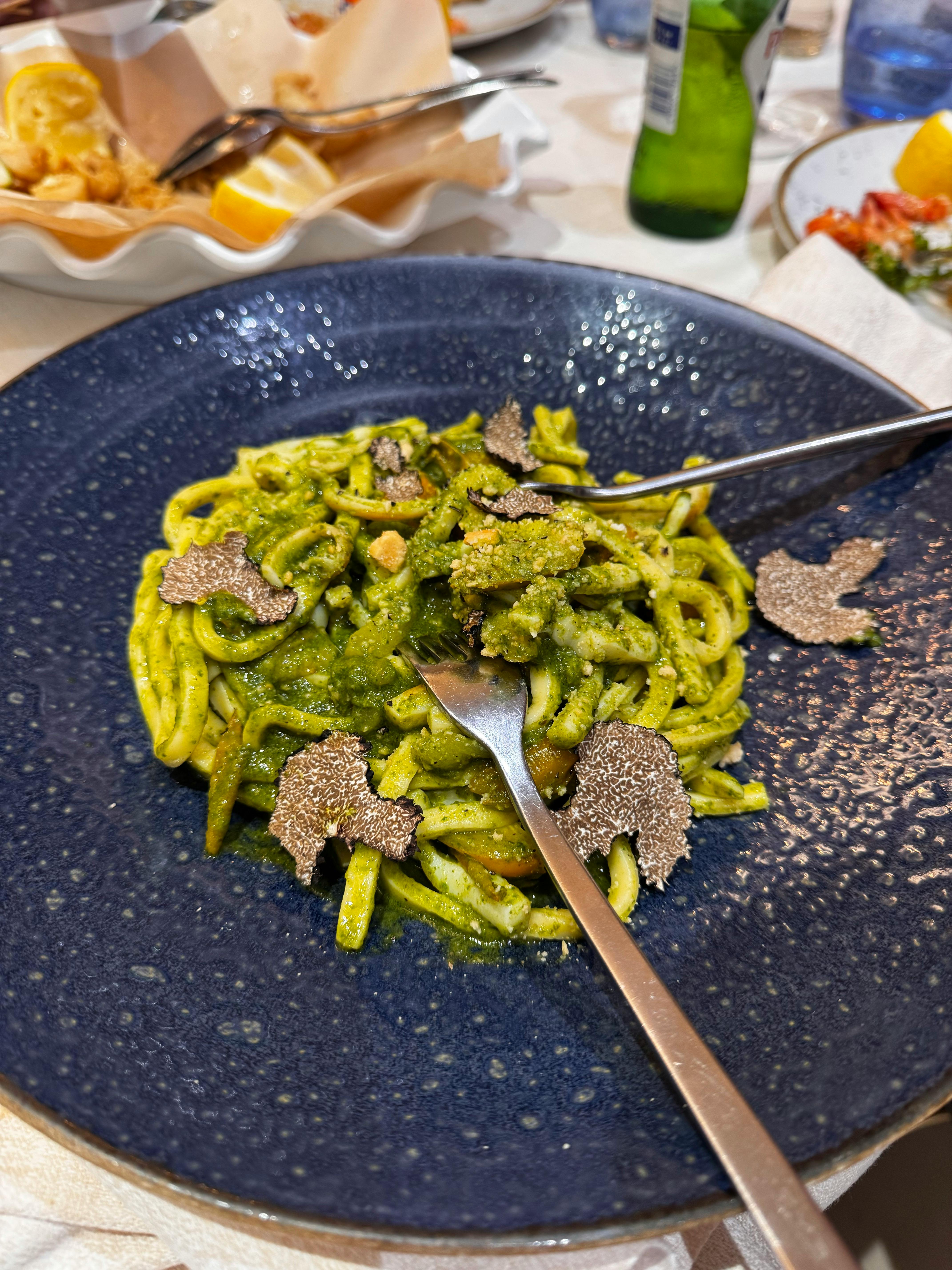 delicious pasta with pesto and truffles on blue plate