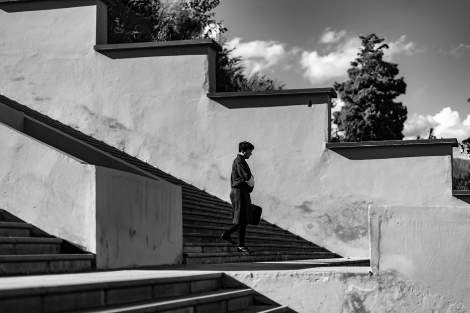 Monochrome photo of a person walking on modern architectural stairs outdoors.