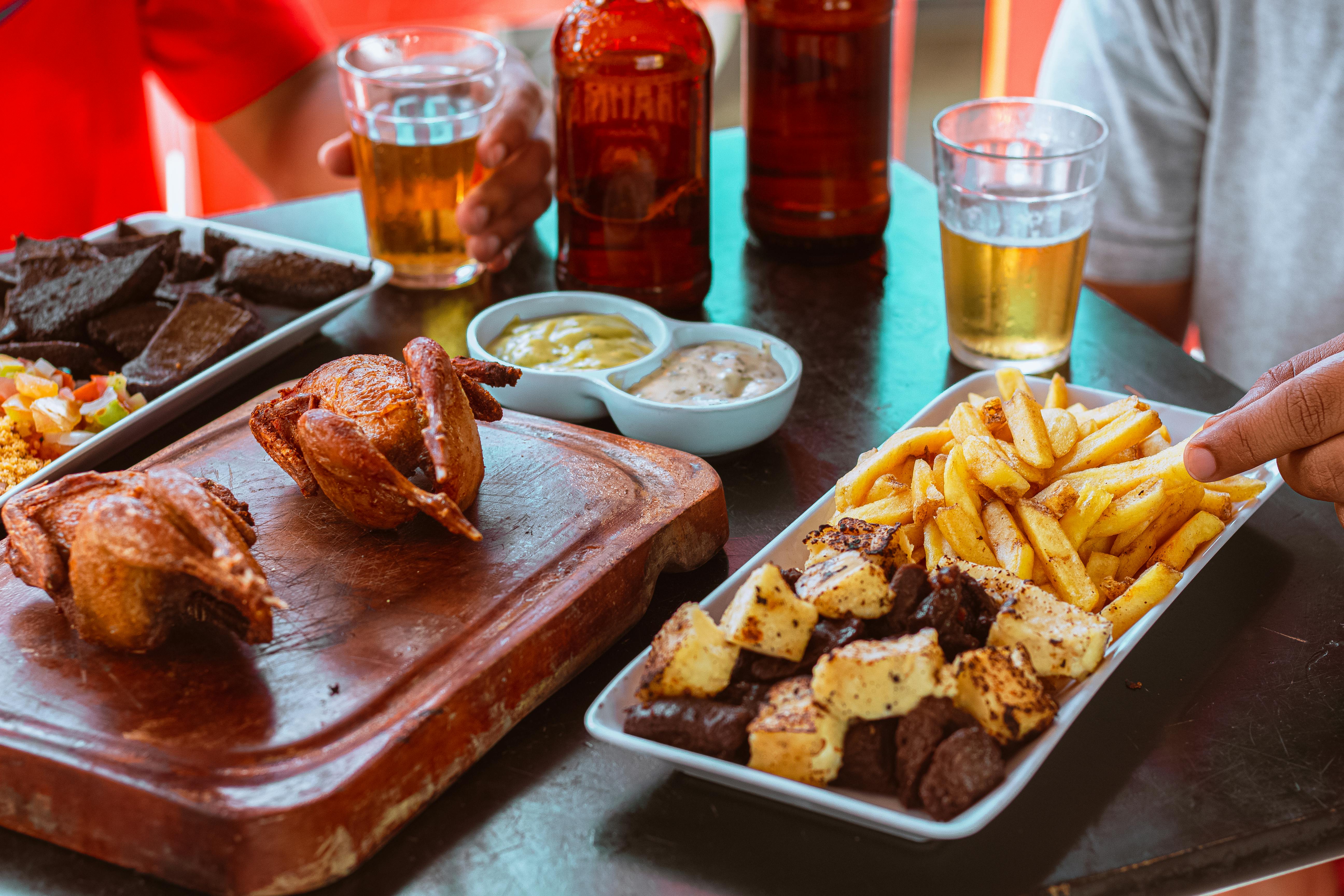 A table with fried chicken, fries, sauces, and beers, perfect for a casual meal.
