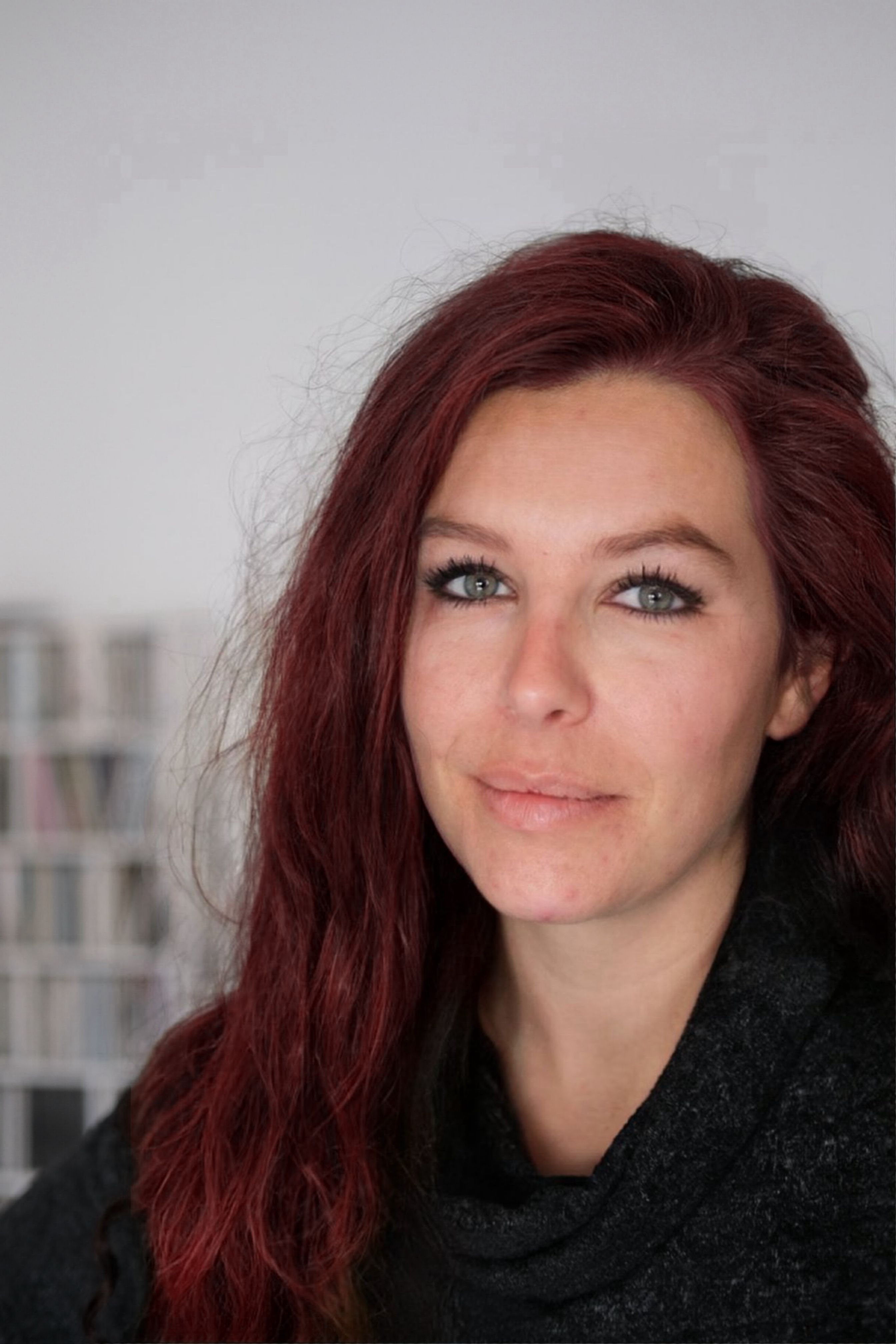 Close-up portrait of an adult woman with red hair and blue eyes, indoors