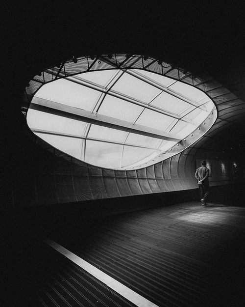 Free Black and white photo of a unique skylight in modern architecture with a lone person walking. Stock Photo