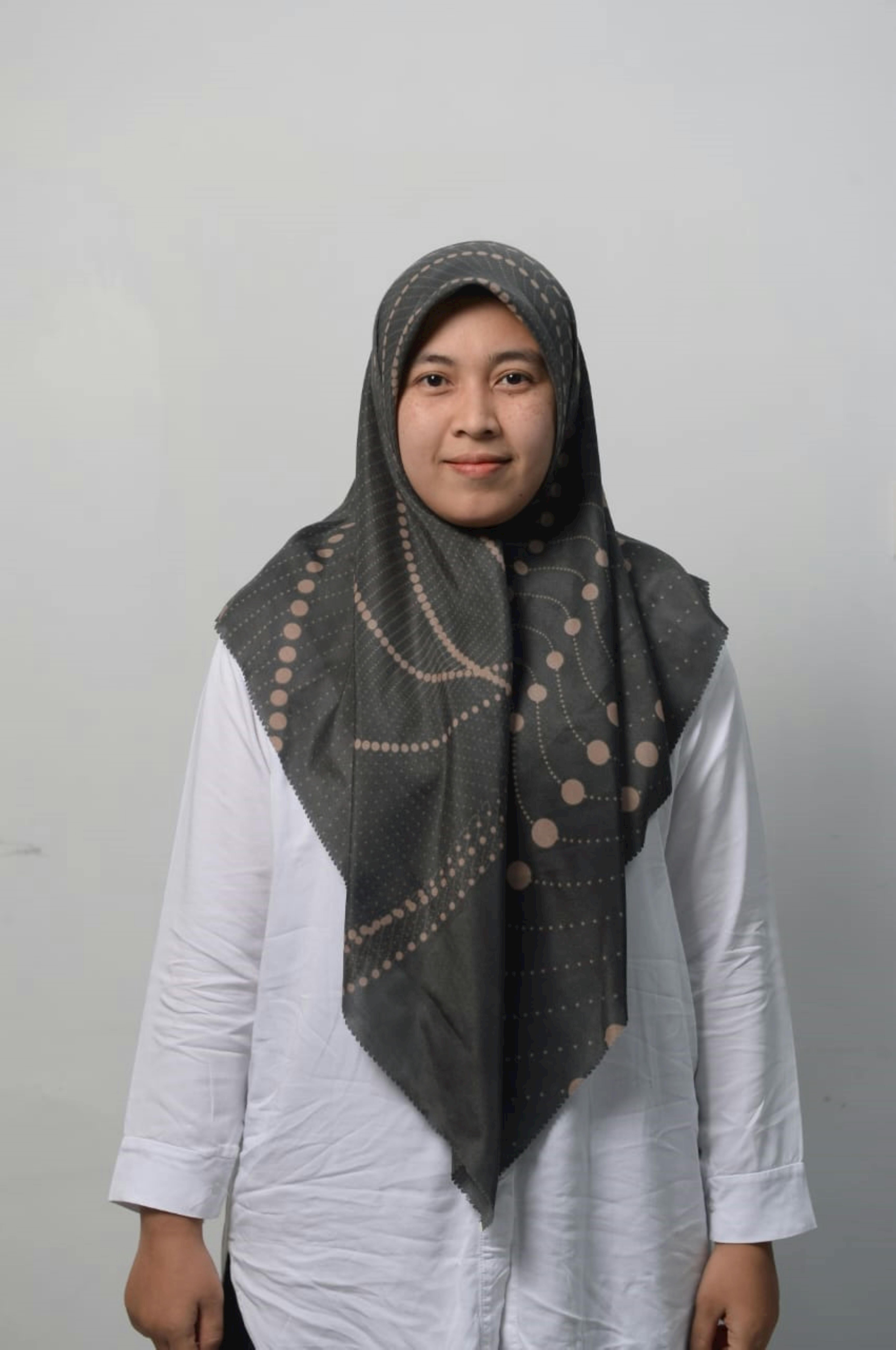 Studio portrait of a smiling woman wearing a patterned hijab and white shirt.