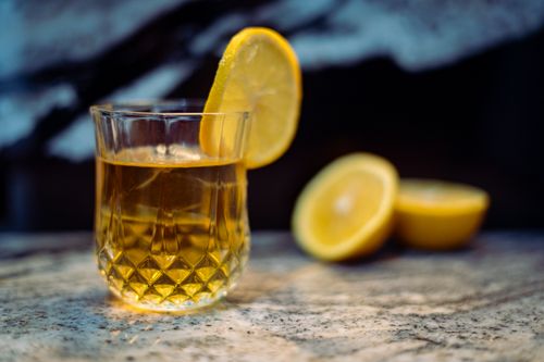 Free A lemon-drink garnished with a slice, placed in an elegant glass on a marble surface. Stock Photo