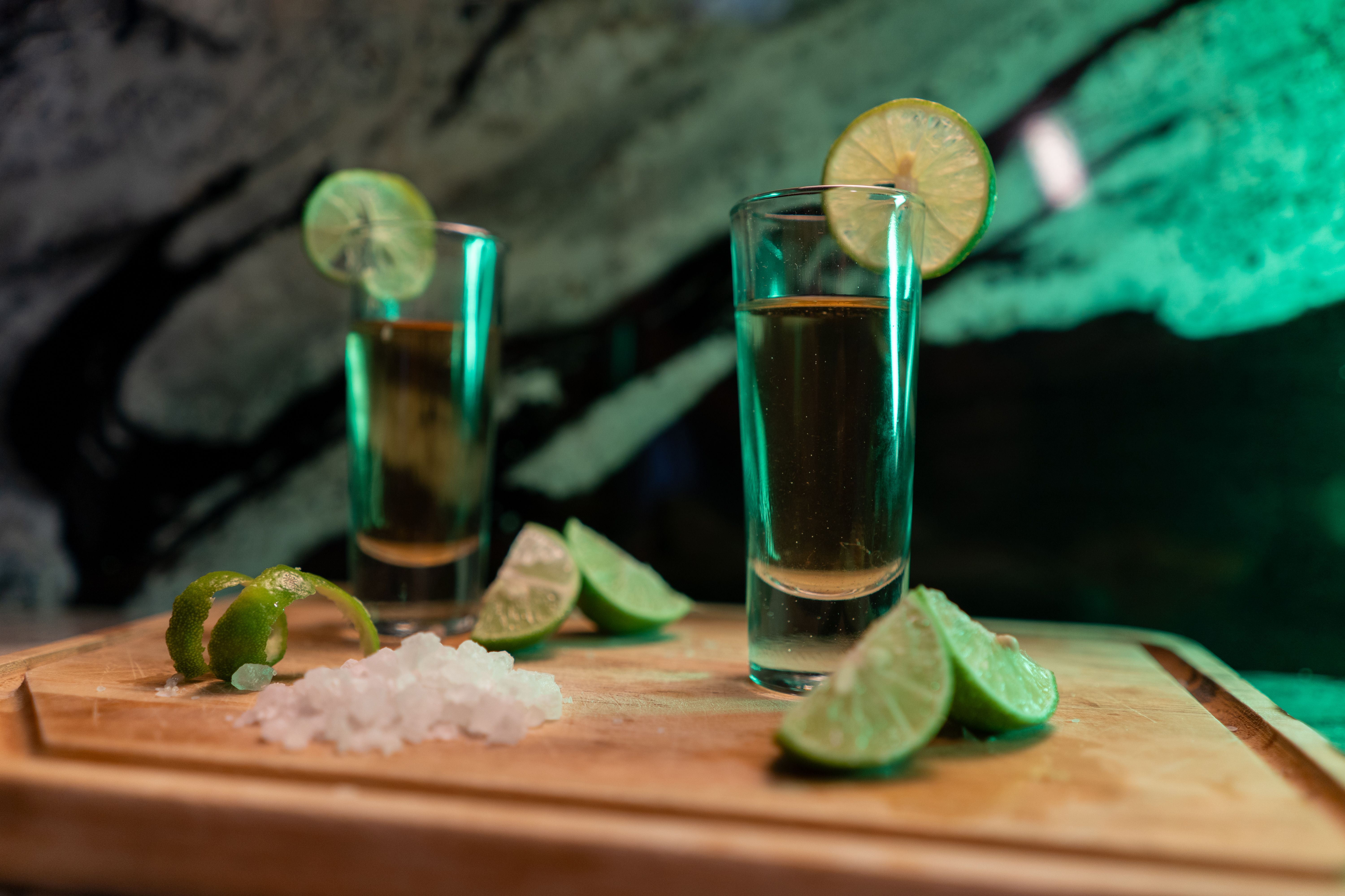 Refreshing tequila shots with lime wedges and salt on a board, perfect for parties.