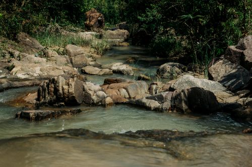 Free Peaceful stream flowing through rocks surrounded by lush greenery in Kon Tum, Vietnam. Stock Photo