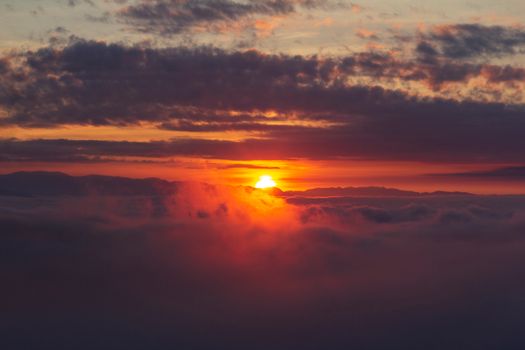 Vibrant sunrise over clouds and mountains in Kon Tum, Vietnam, showcasing a dramatic sky.