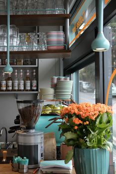 Charming coffee shop interior in Istanbul featuring vibrant flowers and neatly stacked plates.