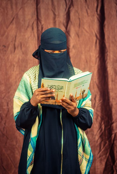 Free A woman in traditional clothing reading the Quran, capturing cultural and religious essence. Stock Photo