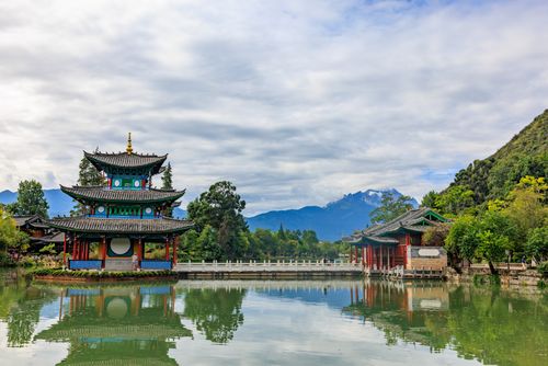 Free Beautiful Asian architecture reflected in a tranquil lake with mountain backdrop. Stock Photo