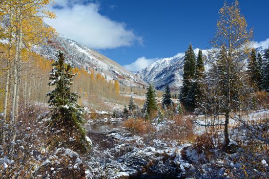 Breathtaking autumn view of Aspen, Colorado with vibrant foliage and fresh snow in the Rocky Mountains.