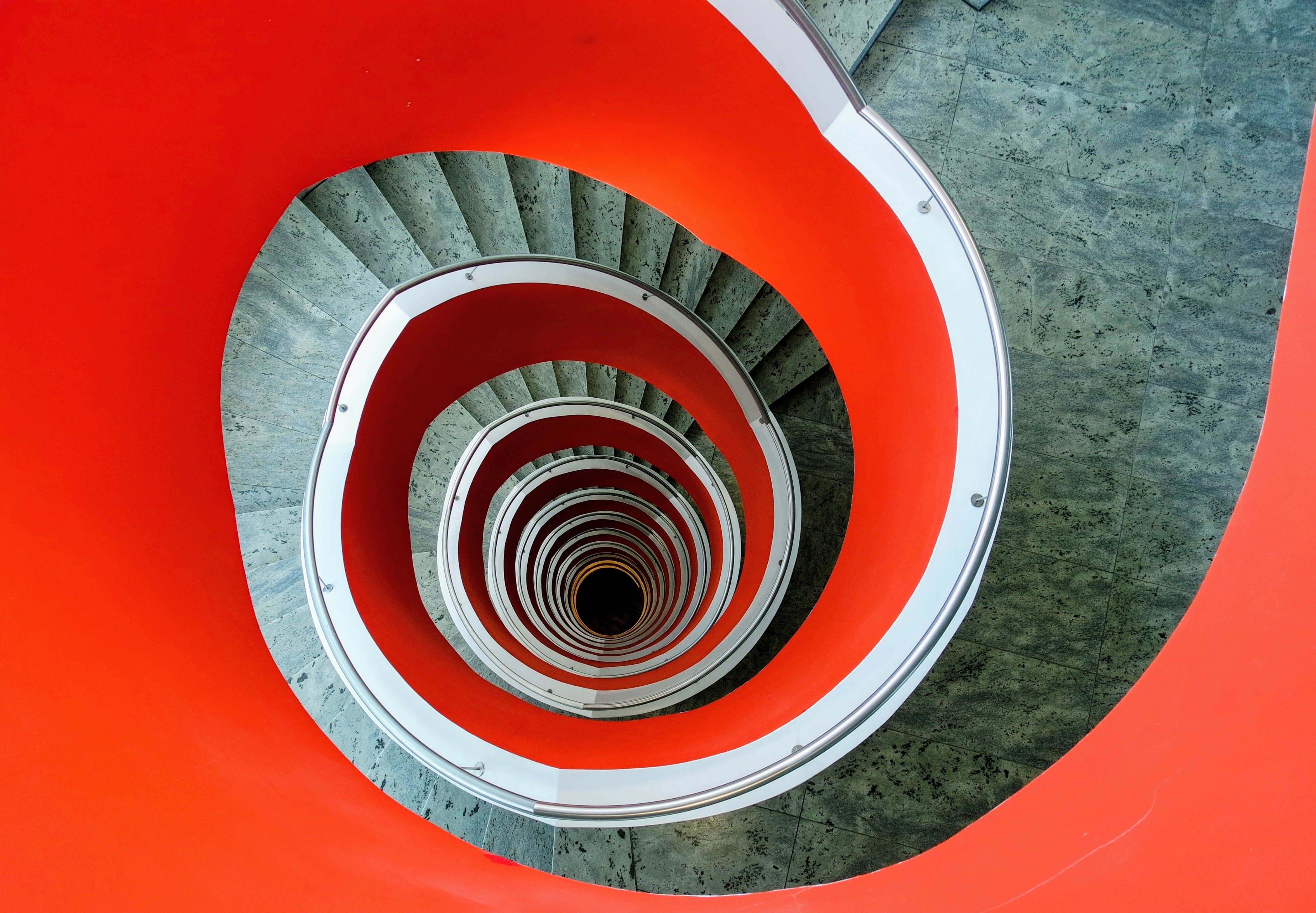 Dynamic view of a modern spiral staircase in Köln, featuring vibrant red railings.