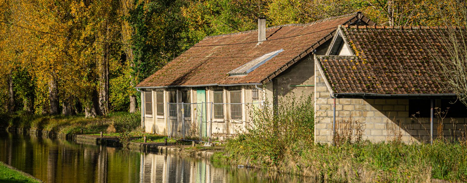Charming rural scene with a rustic house by the canal in autumn at La Ferté-Milon, France.
