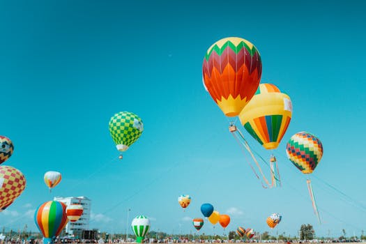 Colorful hot air balloons soar under a clear blue sky in Kon Tum, Vietnam. A stunning aerial festival view.