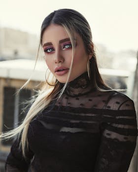 一位优雅的女人，穿着黑色蕾丝上衣，化着醒目的眼妆，正在户外日光下摆姿势