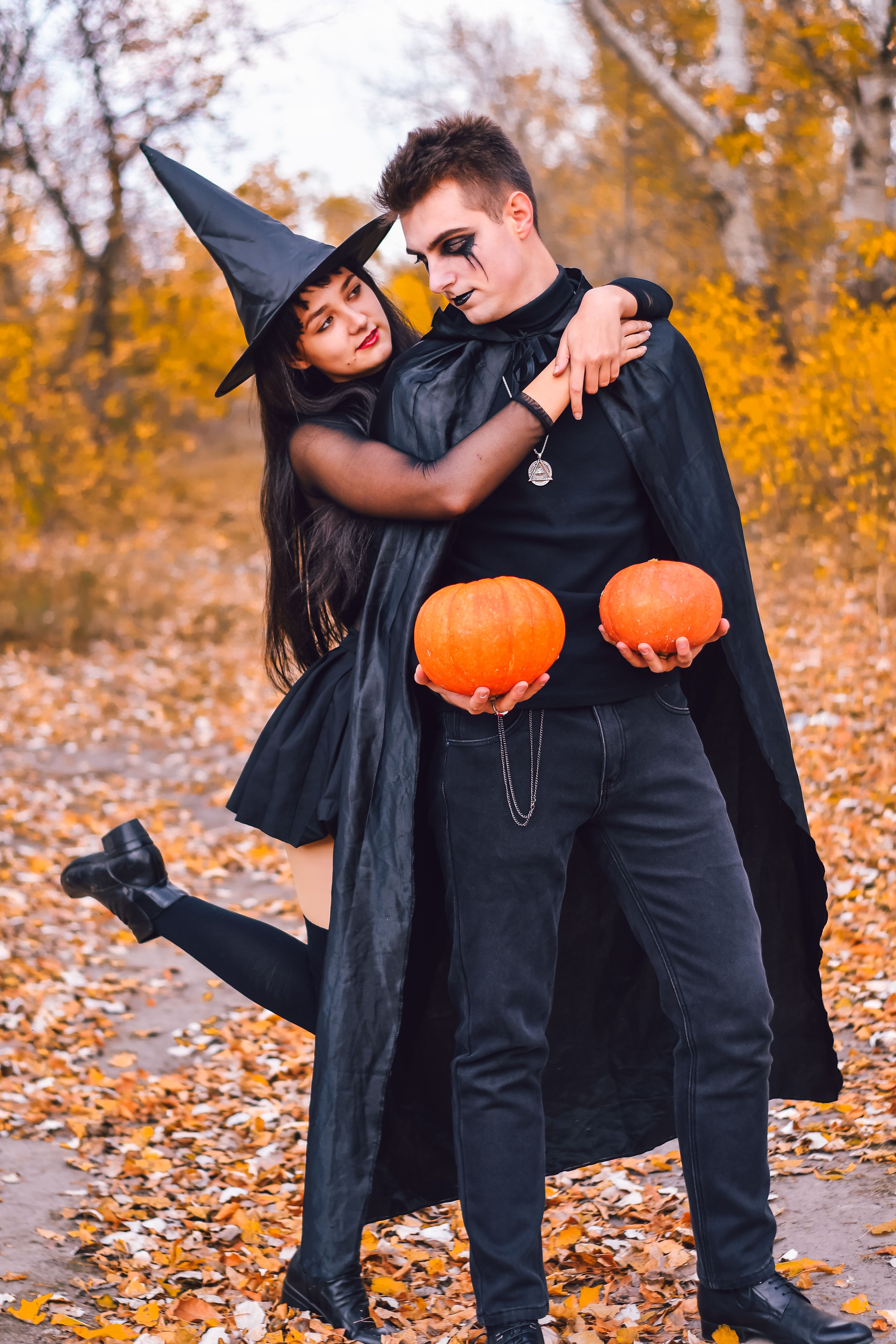 Costumed couple holding pumpkins at a Halloween celebration