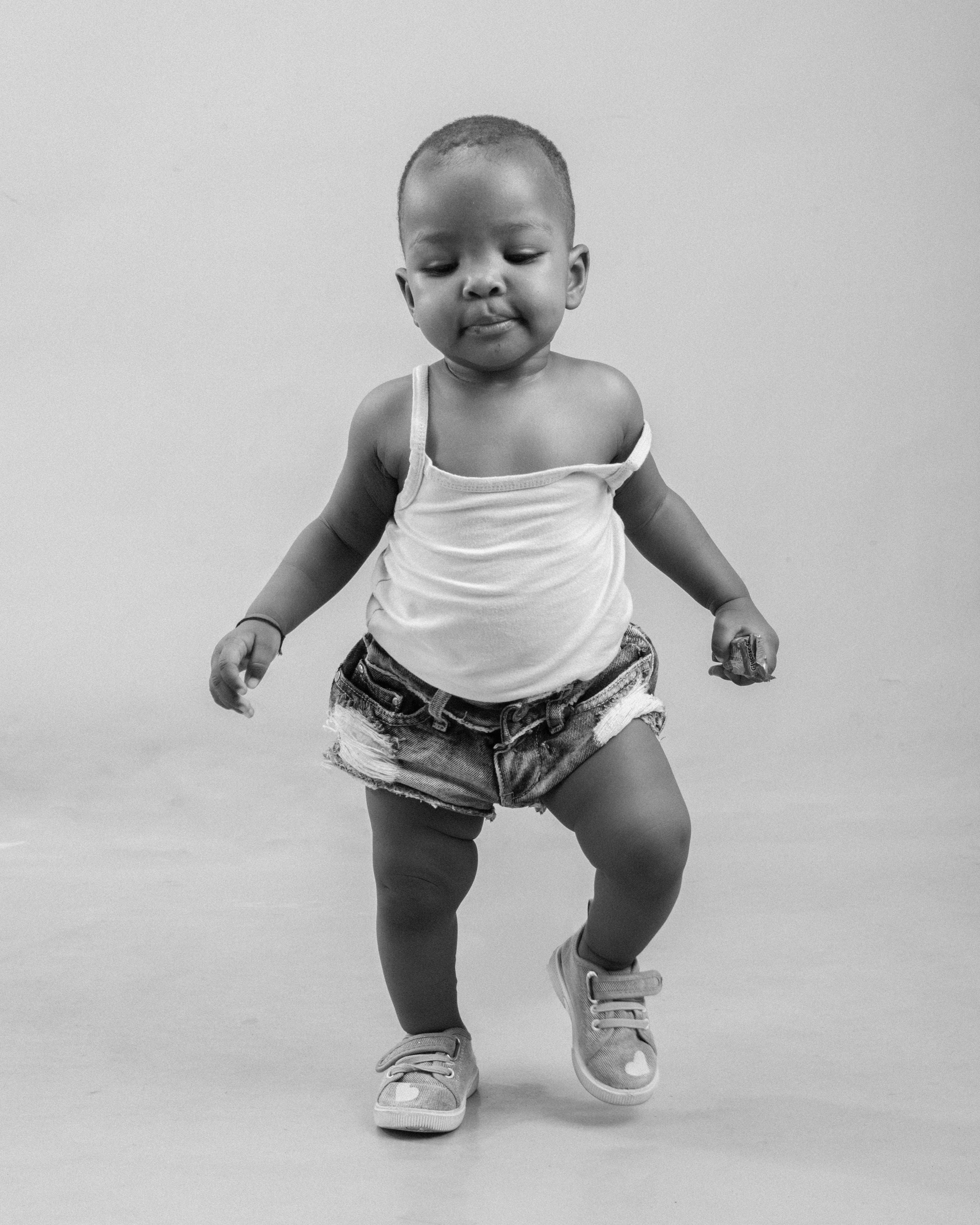Charming portrait of a baby taking first steps, dressed in casual attire.