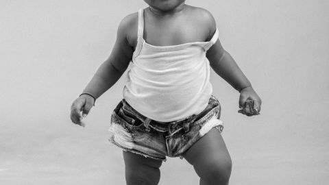 Charming portrait of a baby taking first steps, dressed in casual attire.