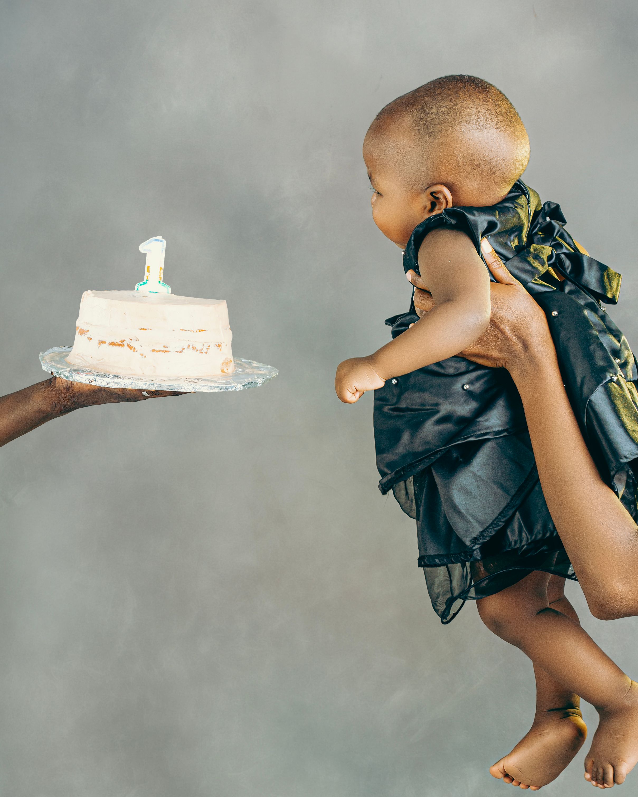 Celebration of a baby's first birthday with a cake featuring a number one candle.