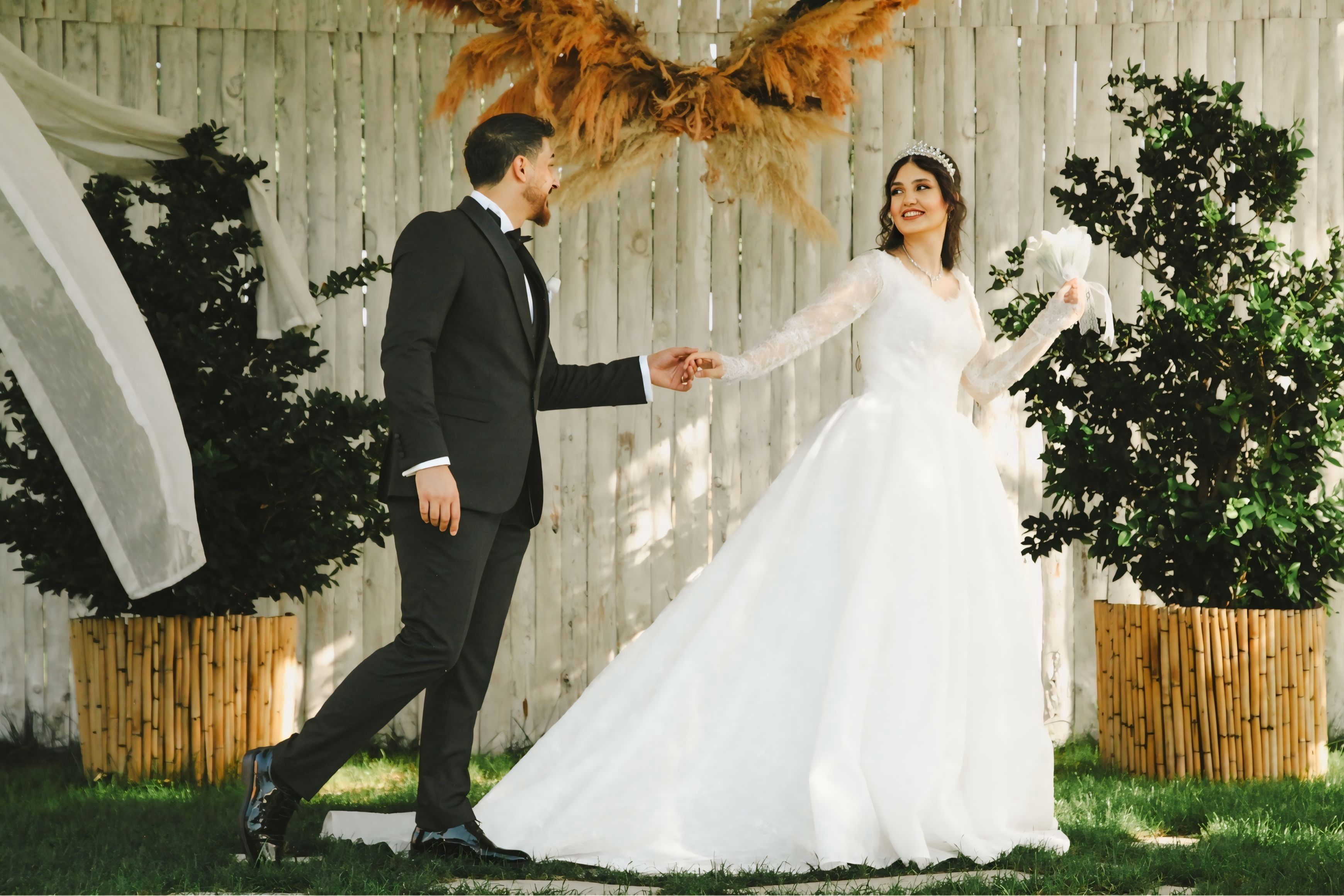 A bride and groom share a joyful moment outdoors at their elegant wedding.