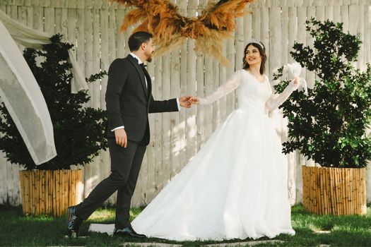 A bride and groom share a joyful moment outdoors at their elegant wedding.