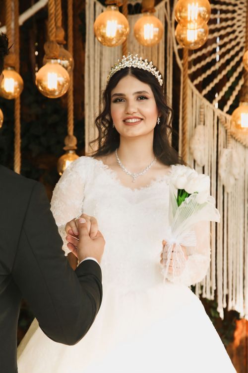 Free Smiling bride holding a bouquet, wearing a tiara, beautifully lit indoors. Stock Photo