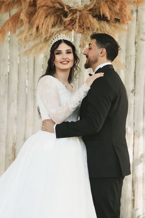 Free A charming couple posed in wedding attire with rustic background. Stock Photo