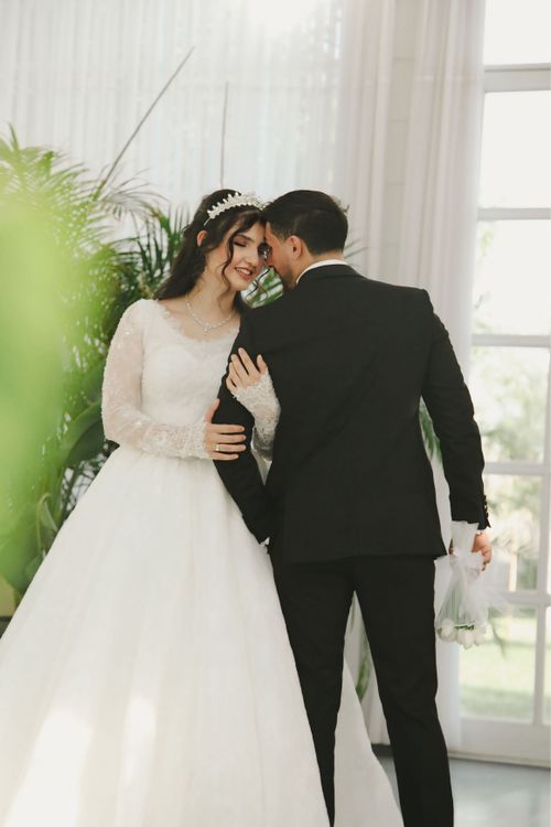 Free A joyful moment between a bride and groom indoors with elegant attire. Stock Photo