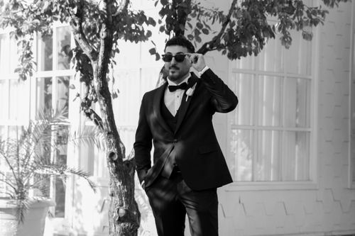 Free A man in a tuxedo adjusts his sunglasses outdoors, exuding elegance and style. Stock Photo