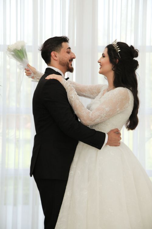 Free Bride and groom embrace happily on their wedding day in a beautifully lit indoor setting. Stock Photo