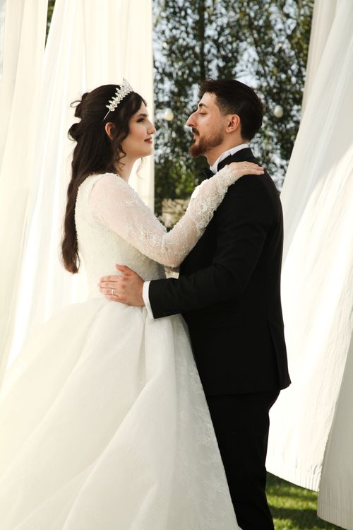 Free Bride and groom embrace outdoors with elegance and love. Stock Photo