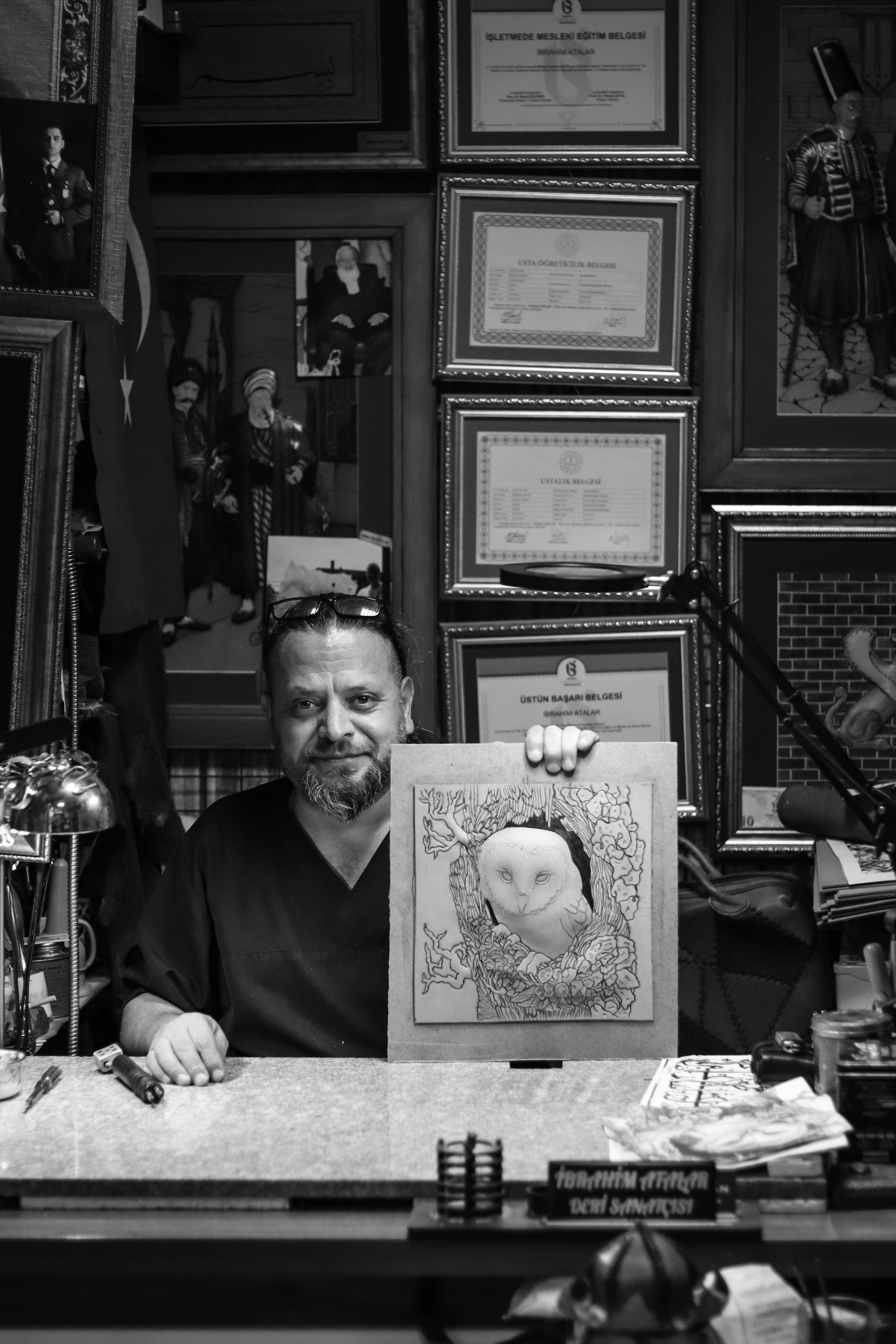 Black and white portrait of an artist in a studio showcasing owl artwork.