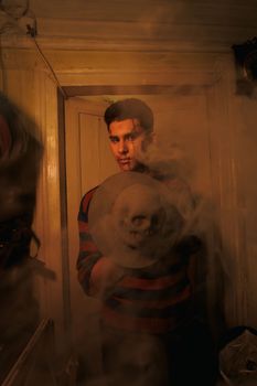 A dramatic, moody portrait of a person indoors with a skull and smoke.