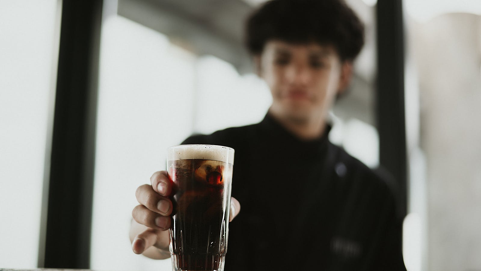 Barista pouring from commercial cold brew dispenser tap into glass