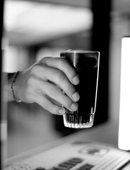 Monochrome image of a hand holding a dark beverage in Provincia de Buenos Aires, Argentina.