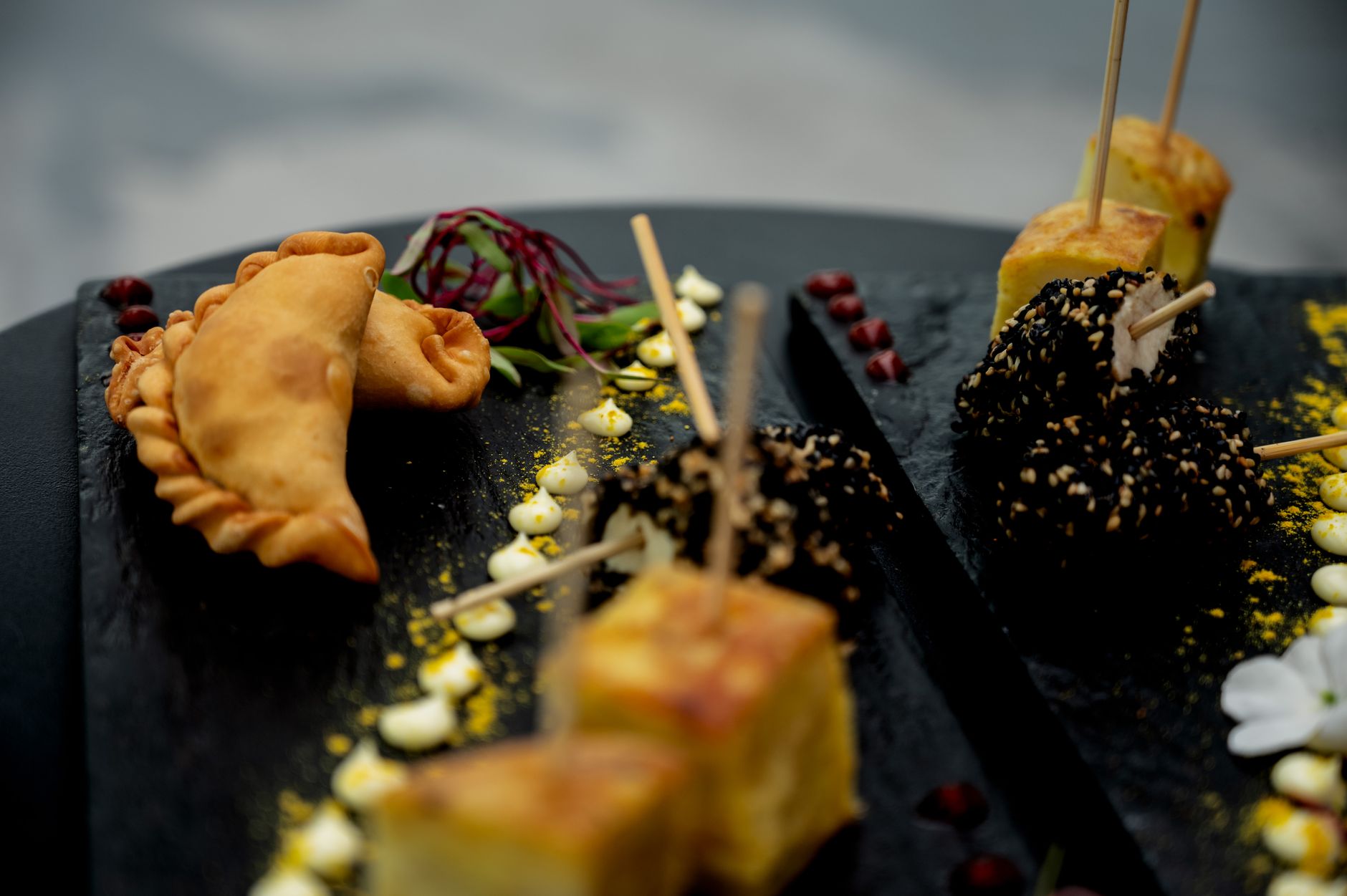 Elegant display of gourmet Argentine appetizers on a black slate with artistic garnishing.