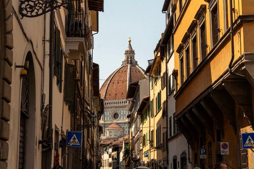 Free A picturesque street in Florence with a view of the iconic cathedral dome, capturing Italian charm. Stock Photo