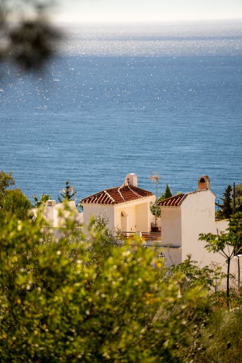 Free Charming white houses in Nerja, Spain, overlooking the sparkling sea under a bright sunny sky. Stock Photo