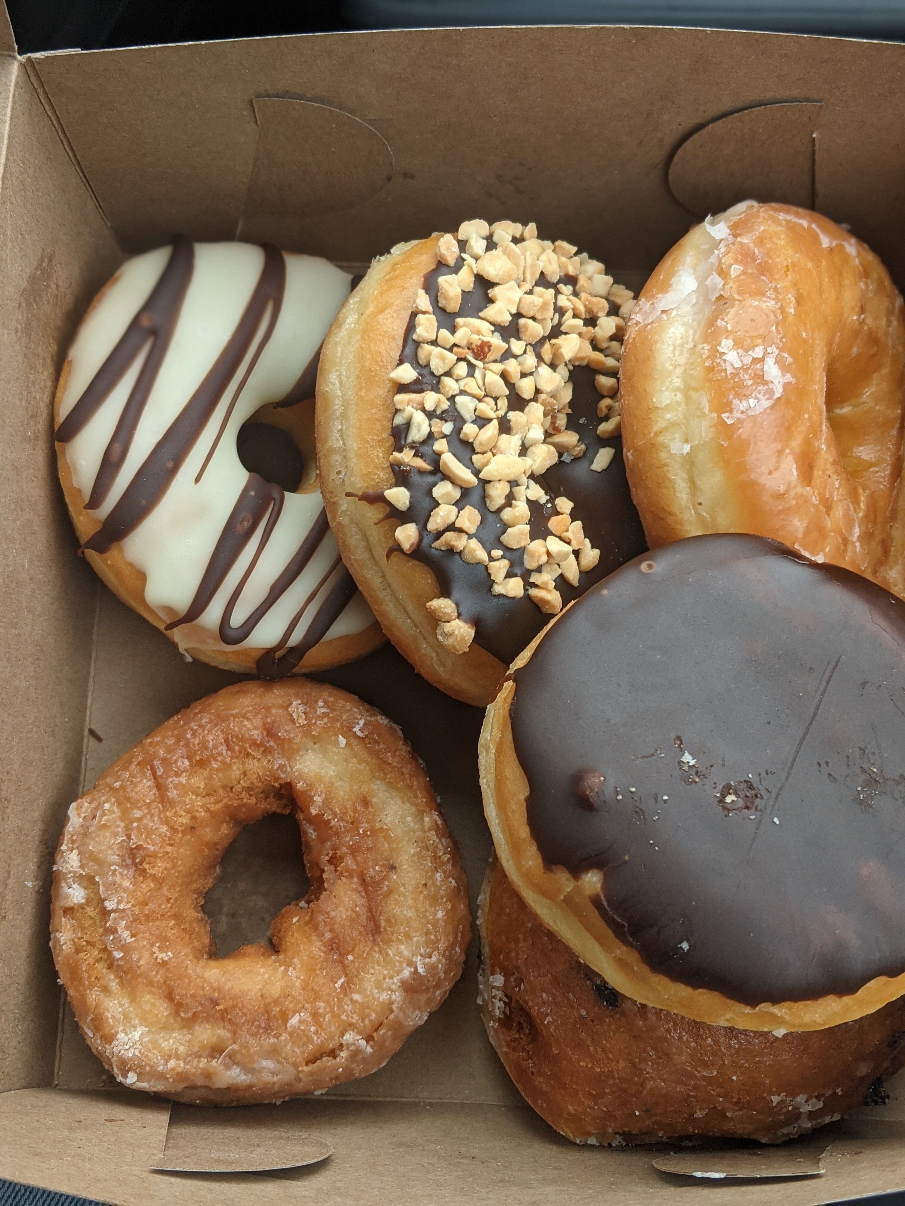 An open box of assorted glazed and chocolate donuts