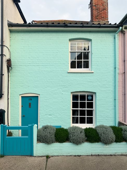 Vibrant pastel-colored house with a teal door in Aldeburgh, showcasing classic English architecture.