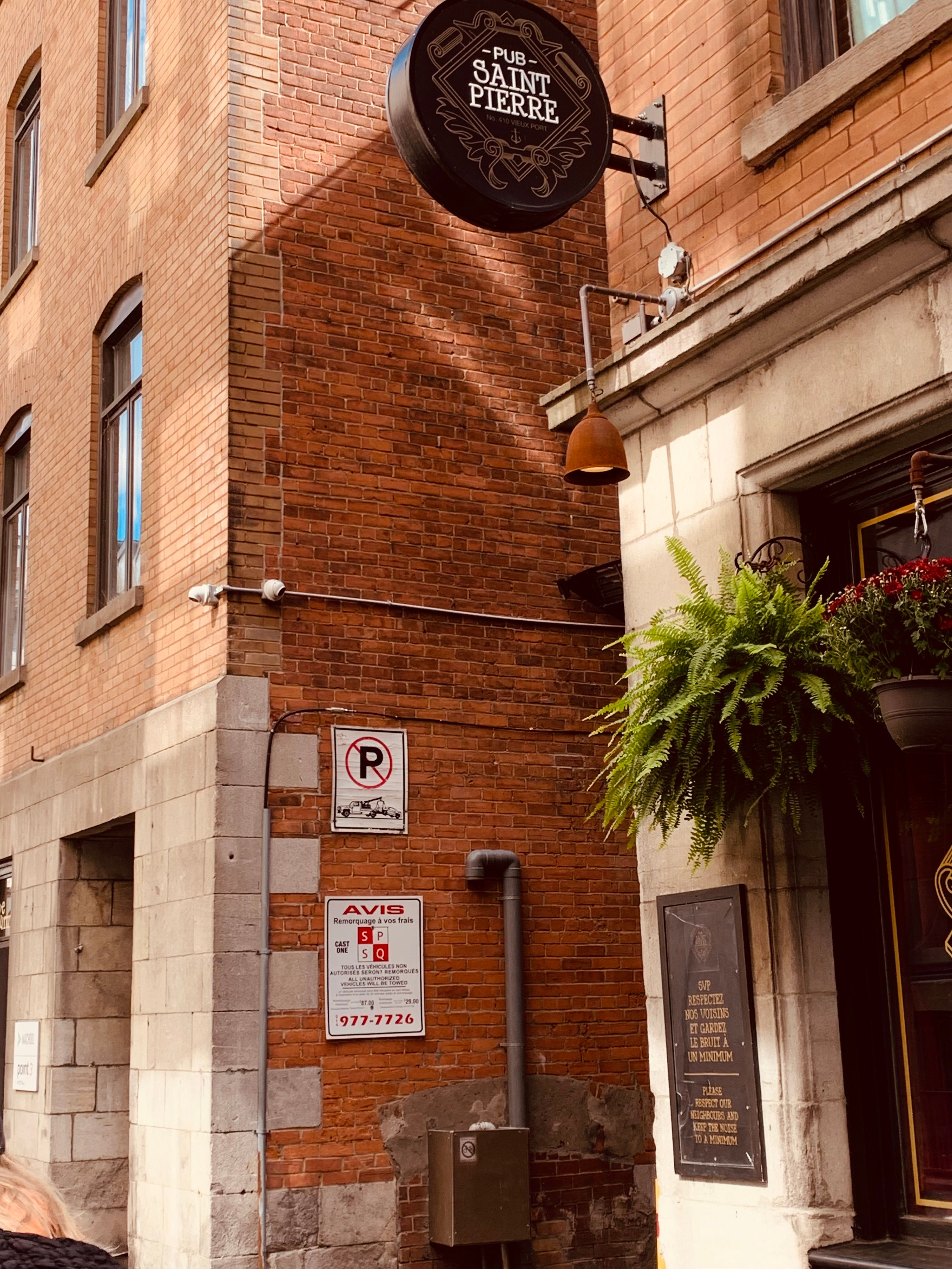 Red brick exterior of a historic pub with signage and green fern.