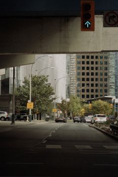 A busy street scene under an overpass in Toronto with traffic and buildings.