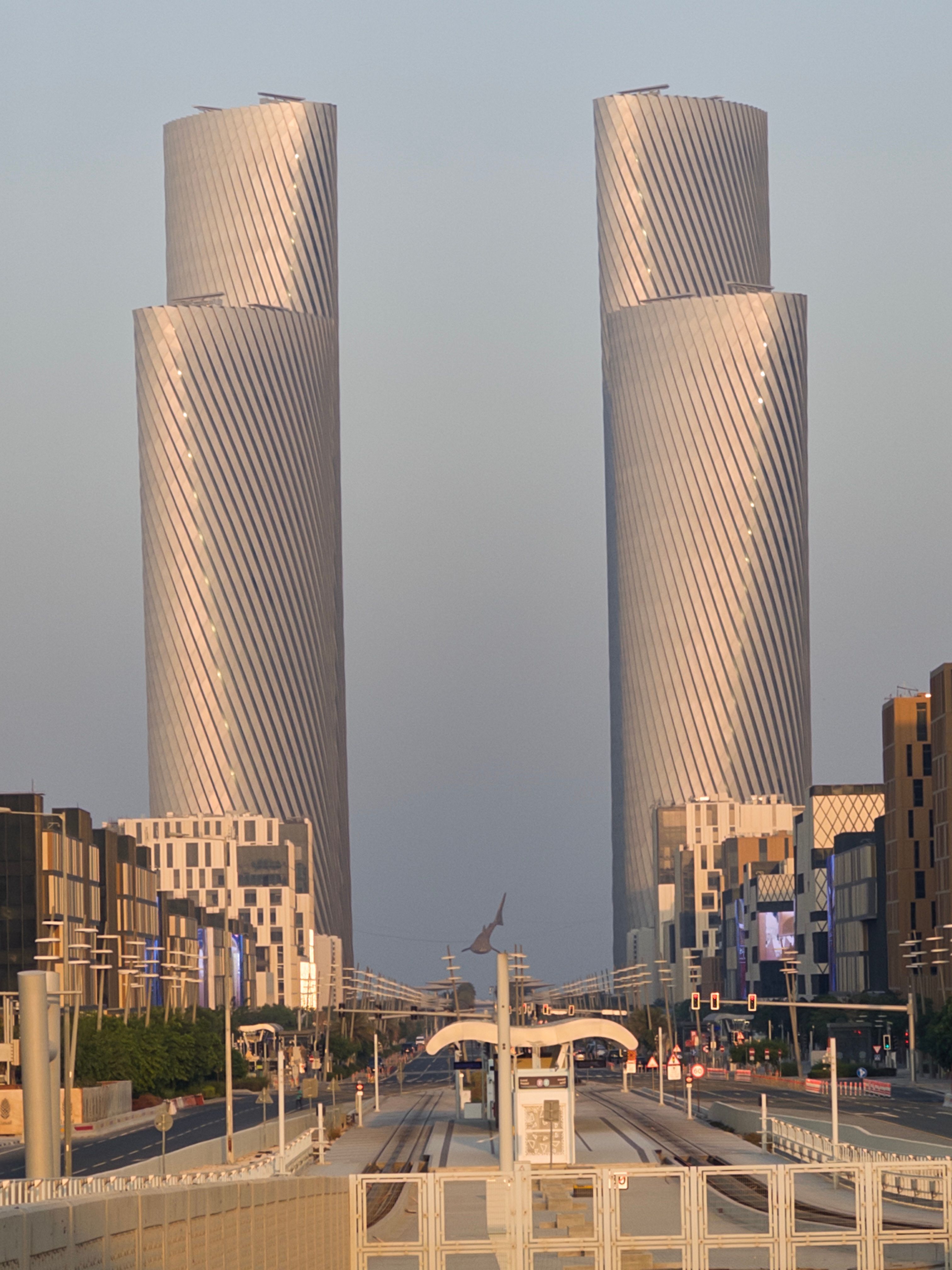Twin modern towers with unique twist design in urban cityscape at dusk
