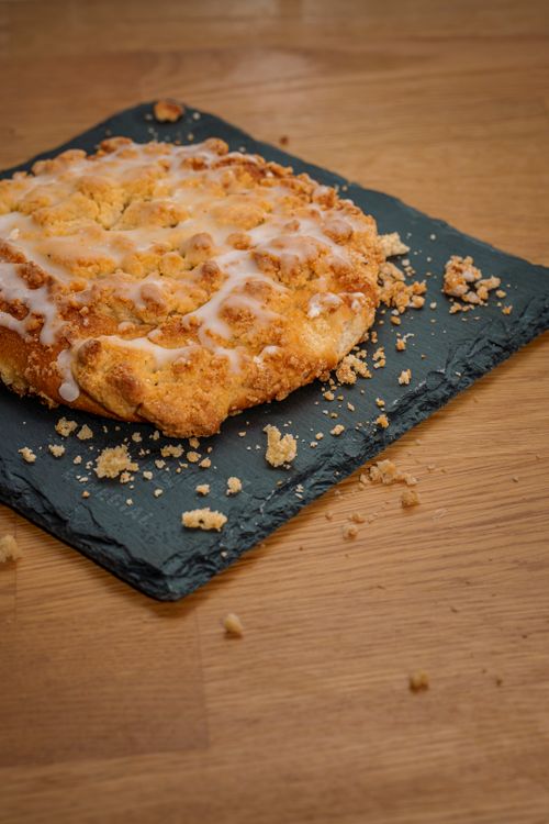 Free A delicious crumb cake with glaze on a rustic slate board, perfect for desserts. Stock Photo