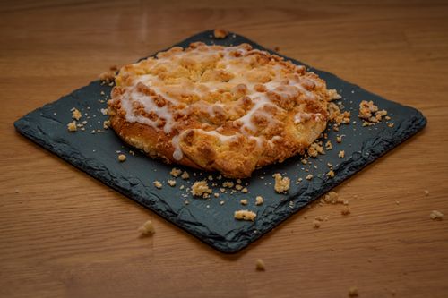 Free Delicious crumble dessert with icing on a black slate plate, on a wooden table. Stock Photo