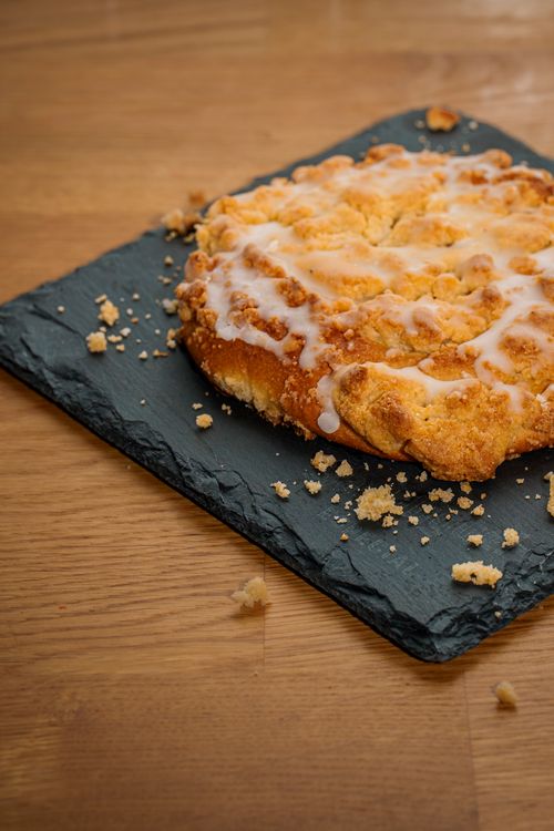 Free Golden coffee cake with vanilla glaze and crumb topping on slate. Stock Photo