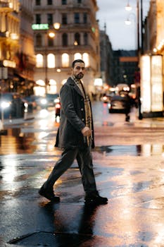 A man crosses a wet street in Vienna, Austria during a moody, rainy evening.