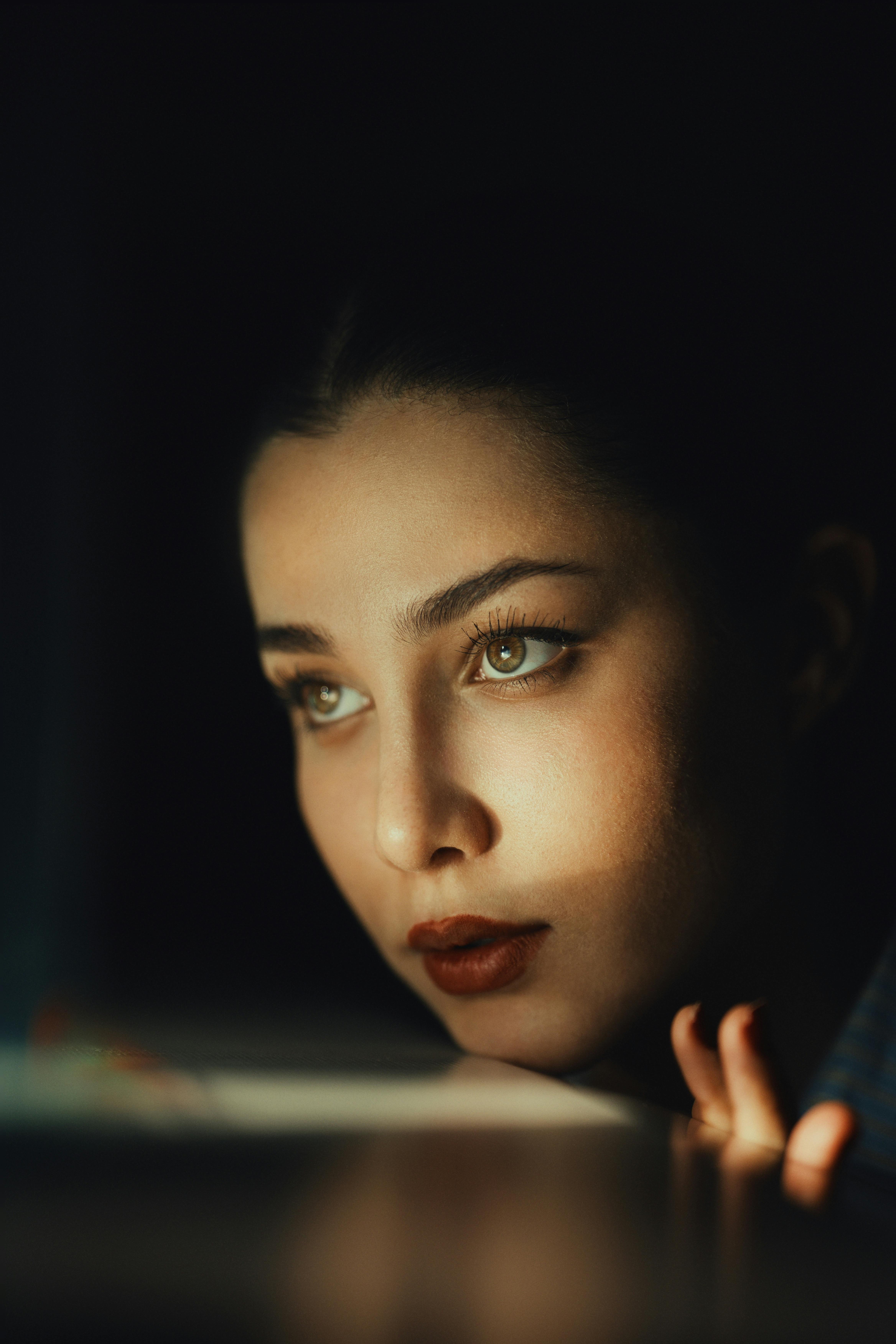 Gratis Il volto di una donna illuminato dalla luce crea un'atmosfera drammatica. Foto a disposizione