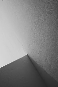 Black and white abstract image of intersecting walls creating geometric shadows.