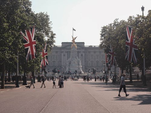 Free A vibrant day at Buckingham Palace with Union Jack flags and tourists exploring. Stock Photo